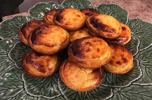 A green plate with Pastel de Nata portuguese pastry arranged on top of it