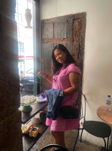 Woman sampling pastries in a pastry shop with sunlight coming in from a window